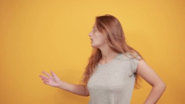 izole turuncu arka plan üzerinde gri t-shirt esmer kız duyguları gösterir