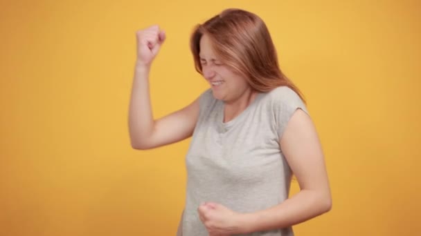 Brunette fille en gris t-shirt sur fond orange isolé montre des émotions — Video