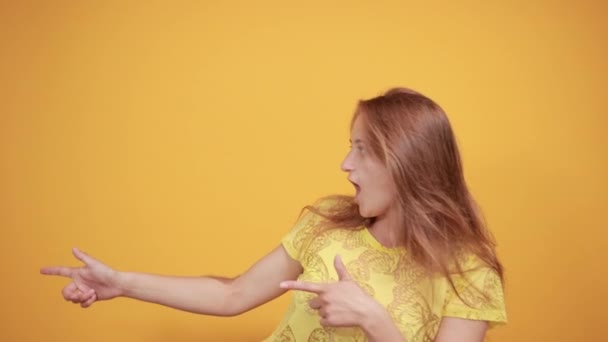 Chica morena en camiseta amarilla sobre fondo naranja aislado muestra emociones — Vídeos de Stock