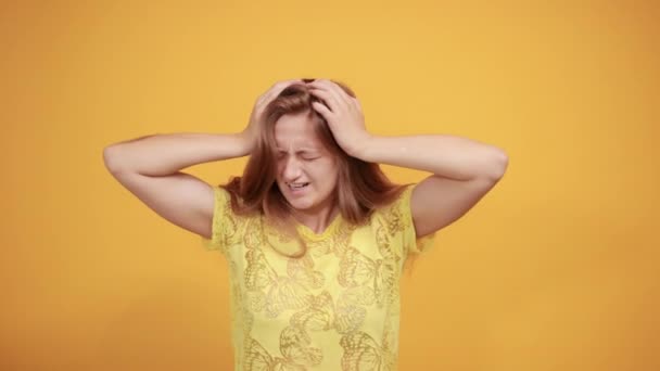 Brunette meisje in geel t-shirt over geïsoleerde oranje achtergrond toont emoties — Stockvideo