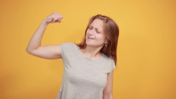 Brunette meisje in grijs t-shirt over geïsoleerde oranje achtergrond toont emoties — Stockvideo
