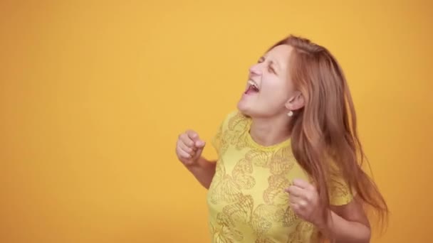 Chica morena en camiseta amarilla sobre fondo naranja aislado muestra emociones — Vídeos de Stock