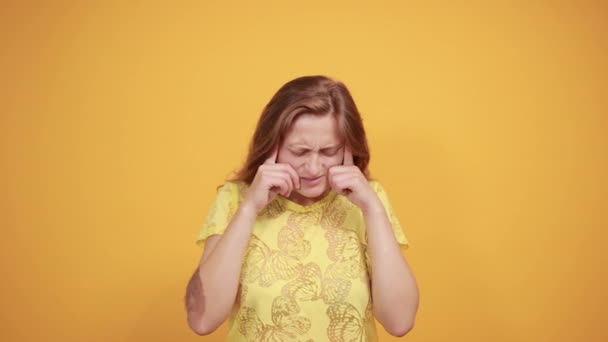 Chica morena en camiseta amarilla sobre fondo naranja aislado muestra emociones — Vídeos de Stock