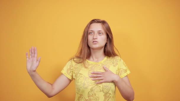 Brünettes Mädchen in gelbem T-Shirt über orangefarbenem Hintergrund zeigt Emotionen — Stockvideo