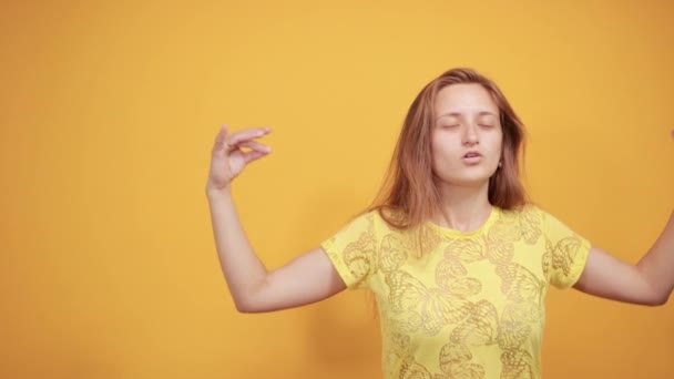 Menina morena em camiseta amarela sobre fundo laranja isolado mostra emoções — Vídeo de Stock