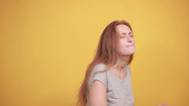 Morena chica en gris camiseta sobre aislado naranja fondo muestra emociones — Vídeo de stock