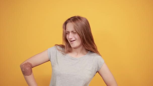 Brunette flicka i grå t-shirt över isolerade orange bakgrund visar känslor — Stockvideo