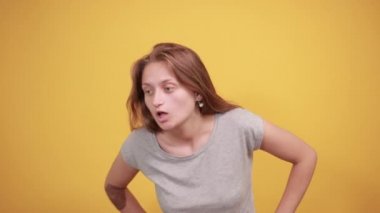 izole turuncu arka plan üzerinde gri t-shirt esmer kız duyguları gösterir