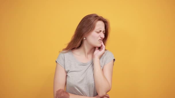 Brunette fille en gris t-shirt sur fond orange isolé montre des émotions — Video