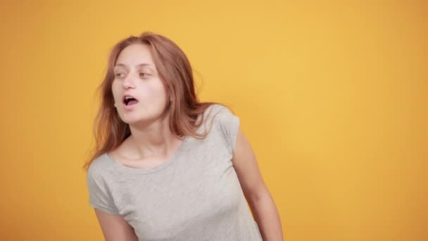 Μελαχρινή κορίτσι σε γκρίζο t-shirt πάνω από απομονωμένο πορτοκαλί φόντο δείχνει τα συναισθήματα — Αρχείο Βίντεο