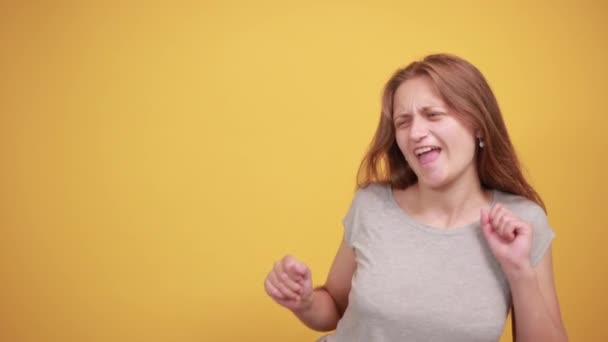 Morena chica en gris camiseta sobre aislado naranja fondo muestra emociones — Vídeo de stock