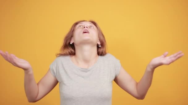 Брюнетка в серой футболке на изолированном оранжевом фоне показывает эмоции — стоковое видео