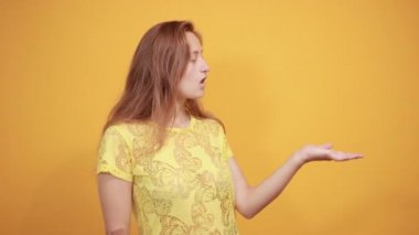izole turuncu arka plan üzerinde sarı t-shirt esmer kız duyguları gösterir