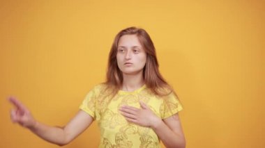 izole turuncu arka plan üzerinde sarı t-shirt esmer kız duyguları gösterir