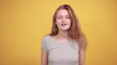izole turuncu arka plan üzerinde gri t-shirt esmer kız duyguları gösterir