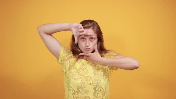 Brunette fille en t-shirt jaune sur fond orange isolé montre des émotions — Video