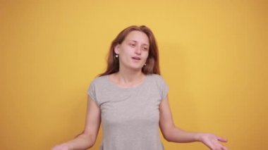 izole turuncu arka plan üzerinde gri t-shirt esmer kız duyguları gösterir