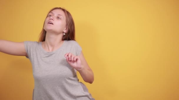 Brunetka dziewczyna w szarym t-shirt na białym tle pomarańczowy pokazuje emocje — Wideo stockowe