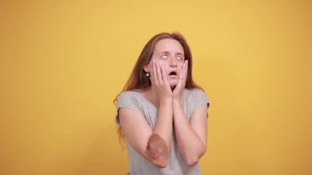 Brunetka v šedém tričku nad ojedinělým oranžovým pozadím vykazuje emoce — Stock video