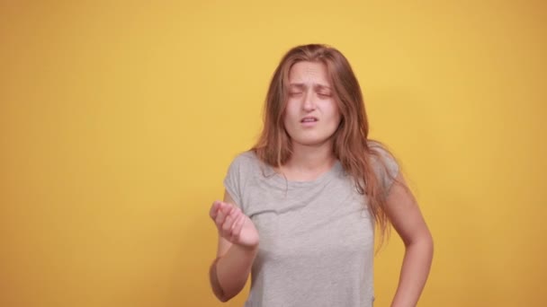 Brunette girl in gray t-shirt over isolated orange background shows emotions — Stock Video