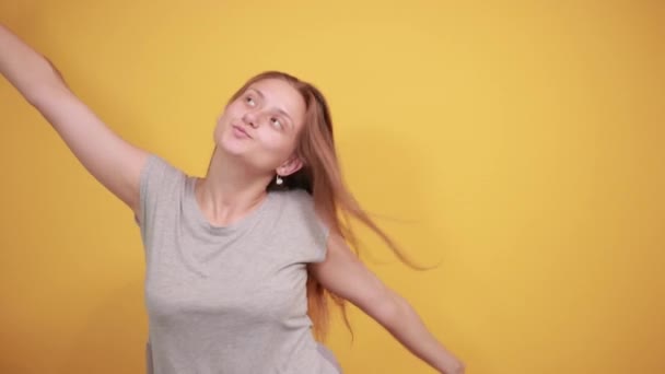 Brunette flicka i grå t-shirt över isolerade orange bakgrund visar känslor — Stockvideo