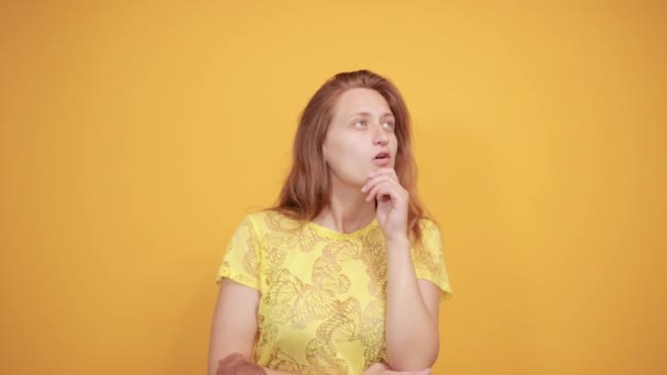 Brunette meisje in geel t-shirt over geïsoleerde oranje achtergrond toont emoties — Stockvideo