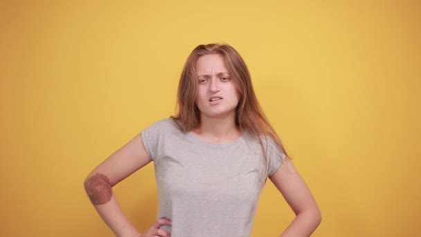 Barna lány szürke t-shirt át elkülönített narancssárga háttér mutatja érzelmek — Stock videók