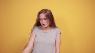 izole turuncu arka plan üzerinde gri t-shirt esmer kız duyguları gösterir