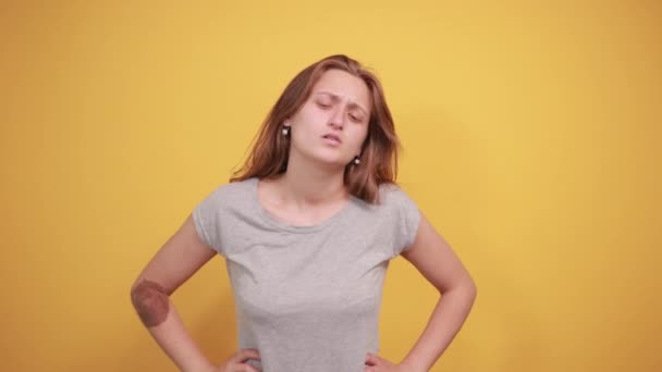 Брюнетка дівчина в сірій футболці над ізольованим помаранчевим тлом показує емоції — стокове відео