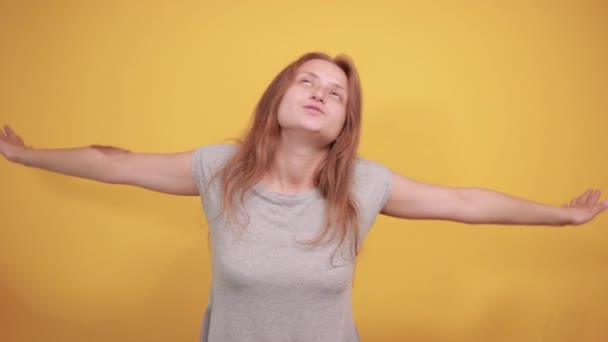 Brunette meisje in grijs t-shirt over geïsoleerde oranje achtergrond toont emoties — Stockvideo