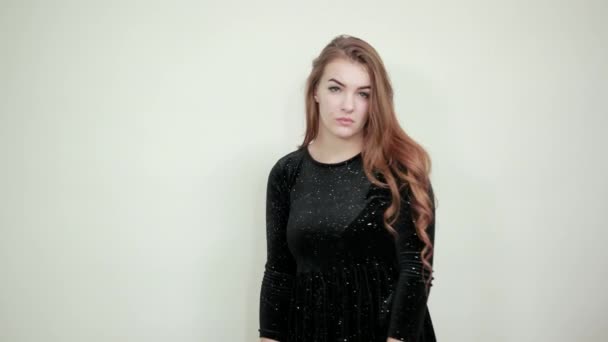Chica de cabello castaño en vestido negro sobre fondo blanco aislado muestra emociones — Vídeo de stock