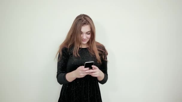 Dziewczyna brązowe włosy w czarnej sukni na białym tle pokazuje emocje — Wideo stockowe
