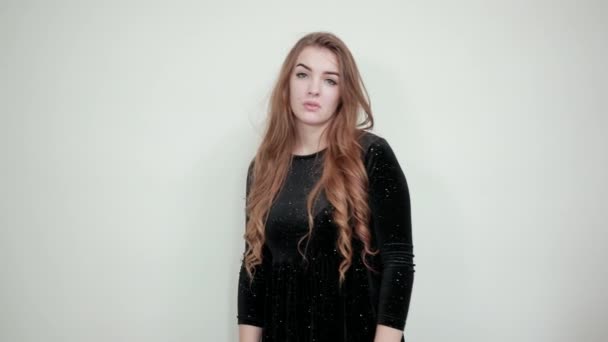 Девушка каштановые волосы в черном платье на изолированном белом фоне показывает эмоции — стоковое видео