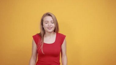 izole turuncu arka plan üzerinde kırmızı t-shirt genç sarışın kız duygularını gösterir