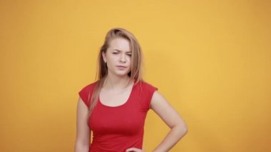 izole turuncu arka plan üzerinde kırmızı t-shirt genç sarışın kız duygularını gösterir