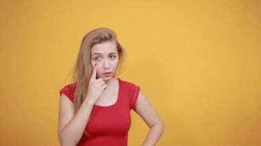 izole turuncu arka plan üzerinde kırmızı t-shirt genç sarışın kız duygularını gösterir