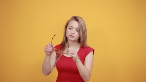 Junges blondes Mädchen in rotem T-Shirt über orangefarbenem Hintergrund zeigt Emotionen — Stockvideo