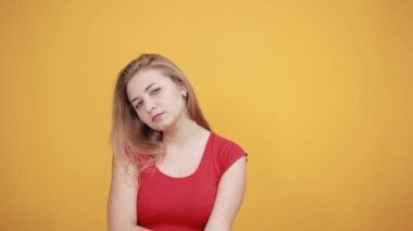 izole turuncu arka plan üzerinde kırmızı t-shirt genç sarışın kız duygularını gösterir