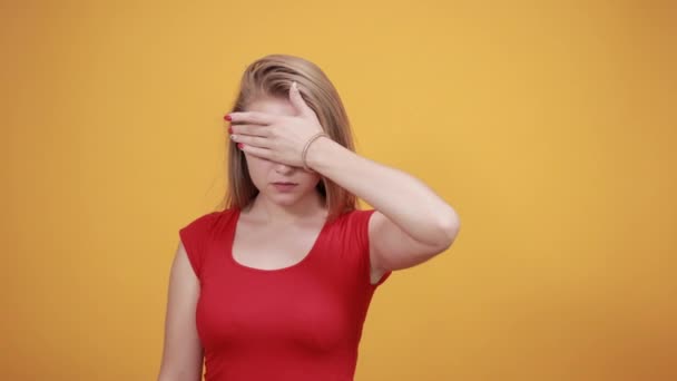 Junges blondes Mädchen in rotem T-Shirt über orangefarbenem Hintergrund zeigt Emotionen — Stockvideo