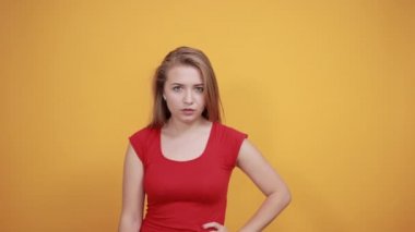 izole turuncu arka plan üzerinde kırmızı t-shirt genç sarışın kız duygularını gösterir