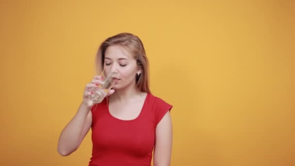 Fiatal szőke lány, piros t-shirt át elkülönített narancssárga háttér mutatja érzelmek — Stock videók