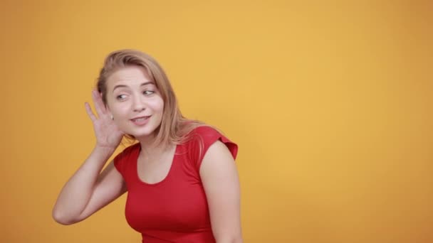 Giovane ragazza bionda in t-shirt rossa su sfondo arancione isolato mostra emozioni — Video Stock