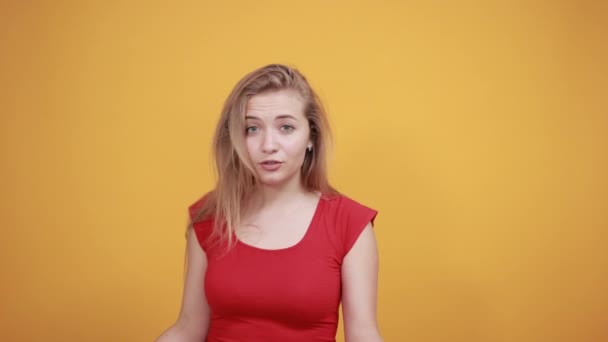 Joven rubia chica en rojo camiseta sobre aislado naranja fondo muestra emociones — Vídeo de stock