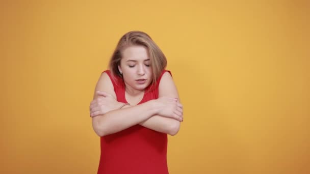 孤立したオレンジの背景の上に赤いTシャツの若いブロンドの女の子は感情を示しています — ストック動画