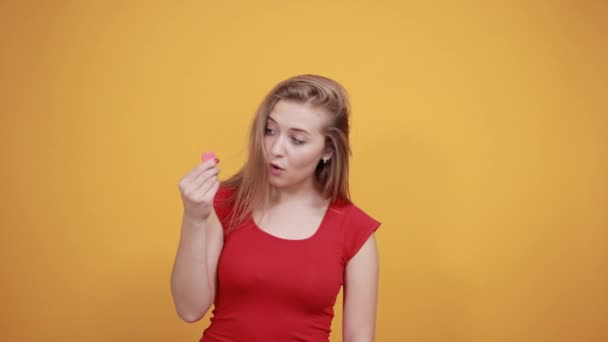 Молода блондинка в червоній футболці над ізольованим помаранчевим тлом показує емоції — стокове відео