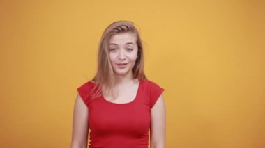 izole turuncu arka plan üzerinde kırmızı t-shirt genç sarışın kız duygularını gösterir