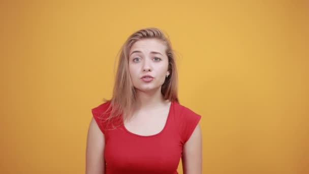 Young blonde girl in red t-shirt over isolated orange background shows emotions — Stock Video