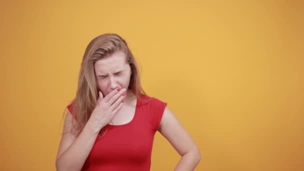 Jeune fille blonde en t-shirt rouge sur fond orange isolé montre des émotions — Video