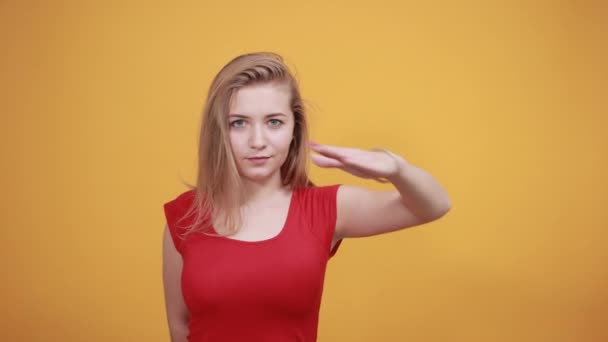 Jeune fille blonde en t-shirt rouge sur fond orange isolé montre des émotions — Video