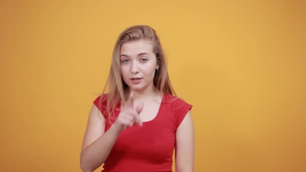 Izole turuncu arka plan üzerinde kırmızı t-shirt genç sarışın kız duygularını gösterir — Stok video